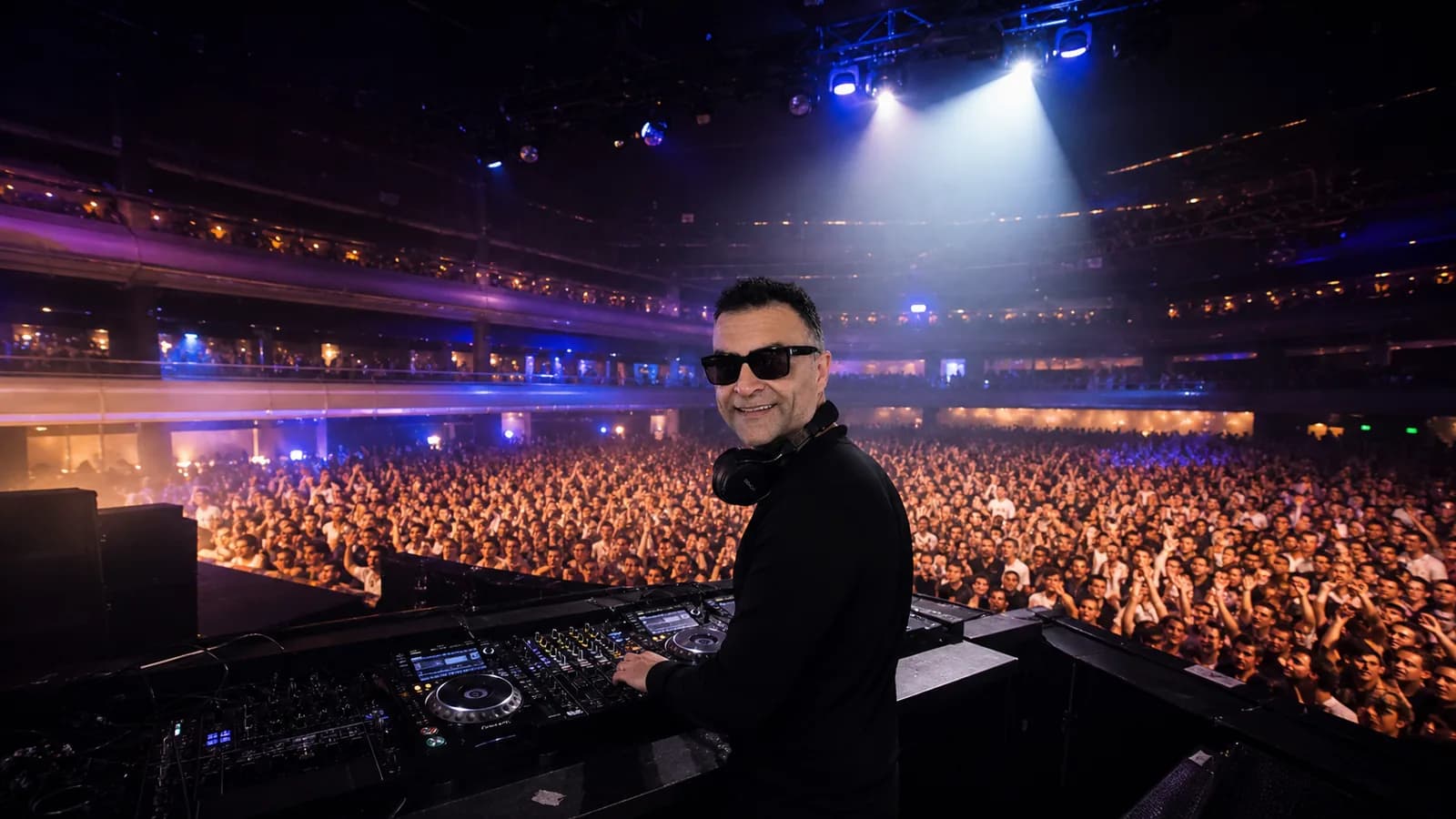 Xavish at the decks facing a large crowd under stage lighting